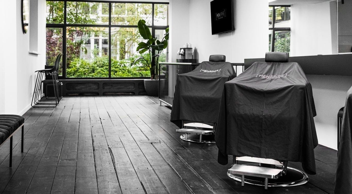 Modern barber chairs at MENSPIRE Old South, Amsterdam, Noord-Holland, NL with lush greenery outside.
