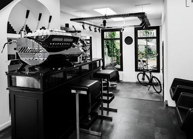 Modern salon lounge at MENSPIRE Old West, Amsterdam, Noord-Holland, NL, featuring sleek seating and a barista station.