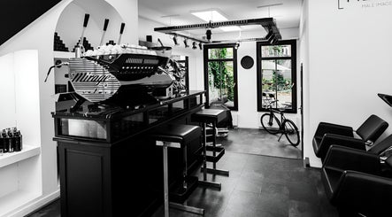 Modern salon lounge at MENSPIRE Old West, Amsterdam, Noord-Holland, NL, featuring sleek seating and a barista station.