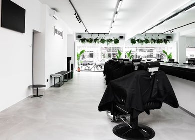 Modern interior of MENSPIRE Beethoven, Amsterdam, Noord-Holland, NL, featuring sleek barber chairs and greenery.