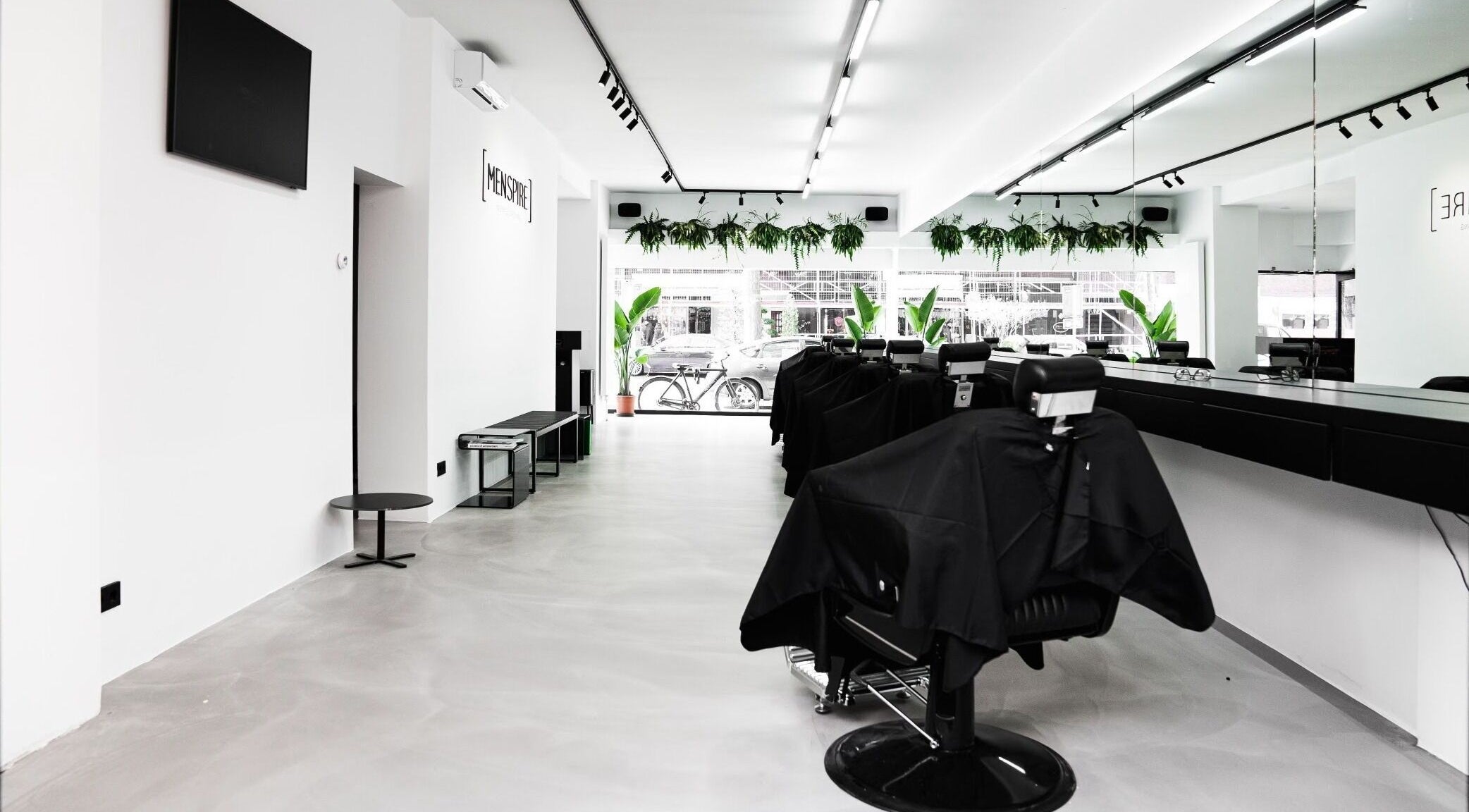 Modern interior of MENSPIRE Beethoven, Amsterdam, Noord-Holland, NL, featuring sleek barber chairs and greenery.