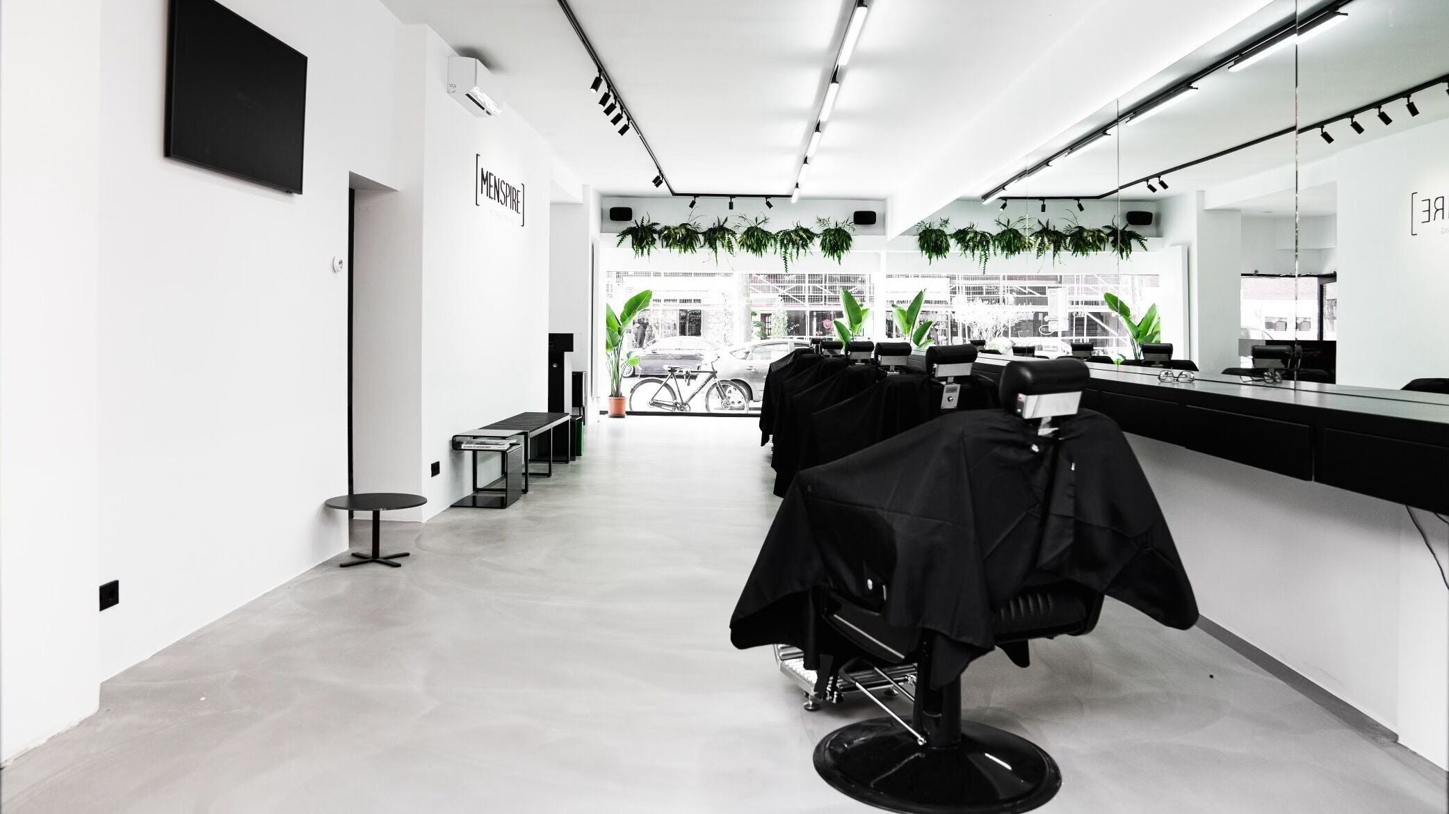 Modern interior of MENSPIRE Beethoven, Amsterdam, Noord-Holland, NL, featuring sleek barber chairs and greenery.