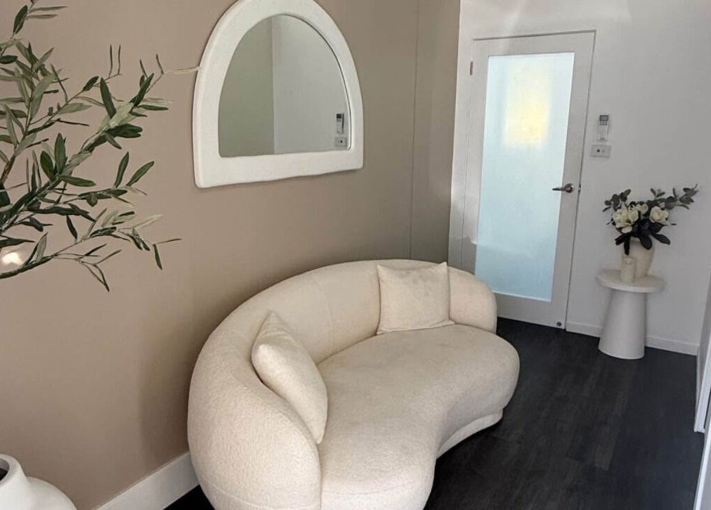 Elegant waiting area at Harmonii Aesthetics, Mermaid Beach, Queensland, AU, featuring a stylish sofa and plants.