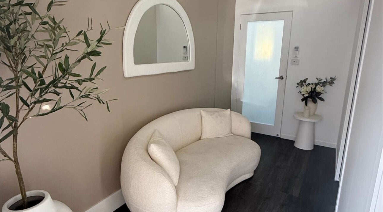 Elegant waiting area at Harmonii Aesthetics, Mermaid Beach, Queensland, AU, featuring a stylish sofa and plants.