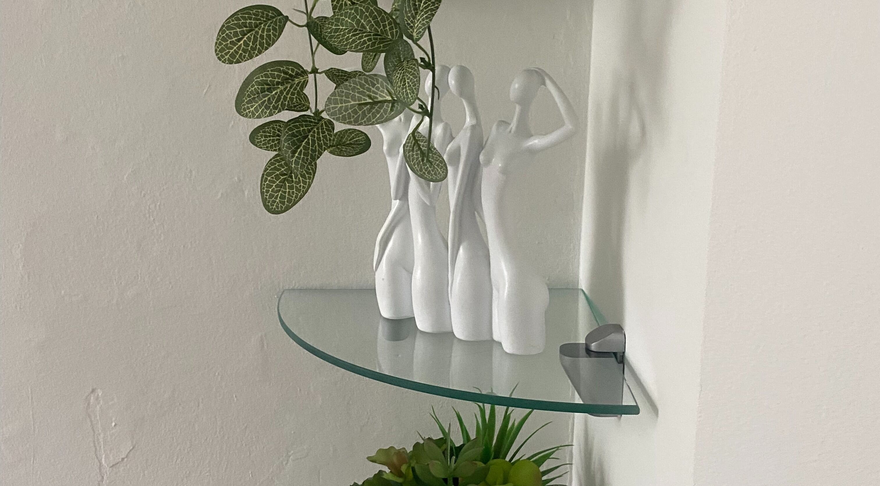 Elegant statuettes and plants on glass shelf at Hude, Royal Tunbridge Wells, England, GB.