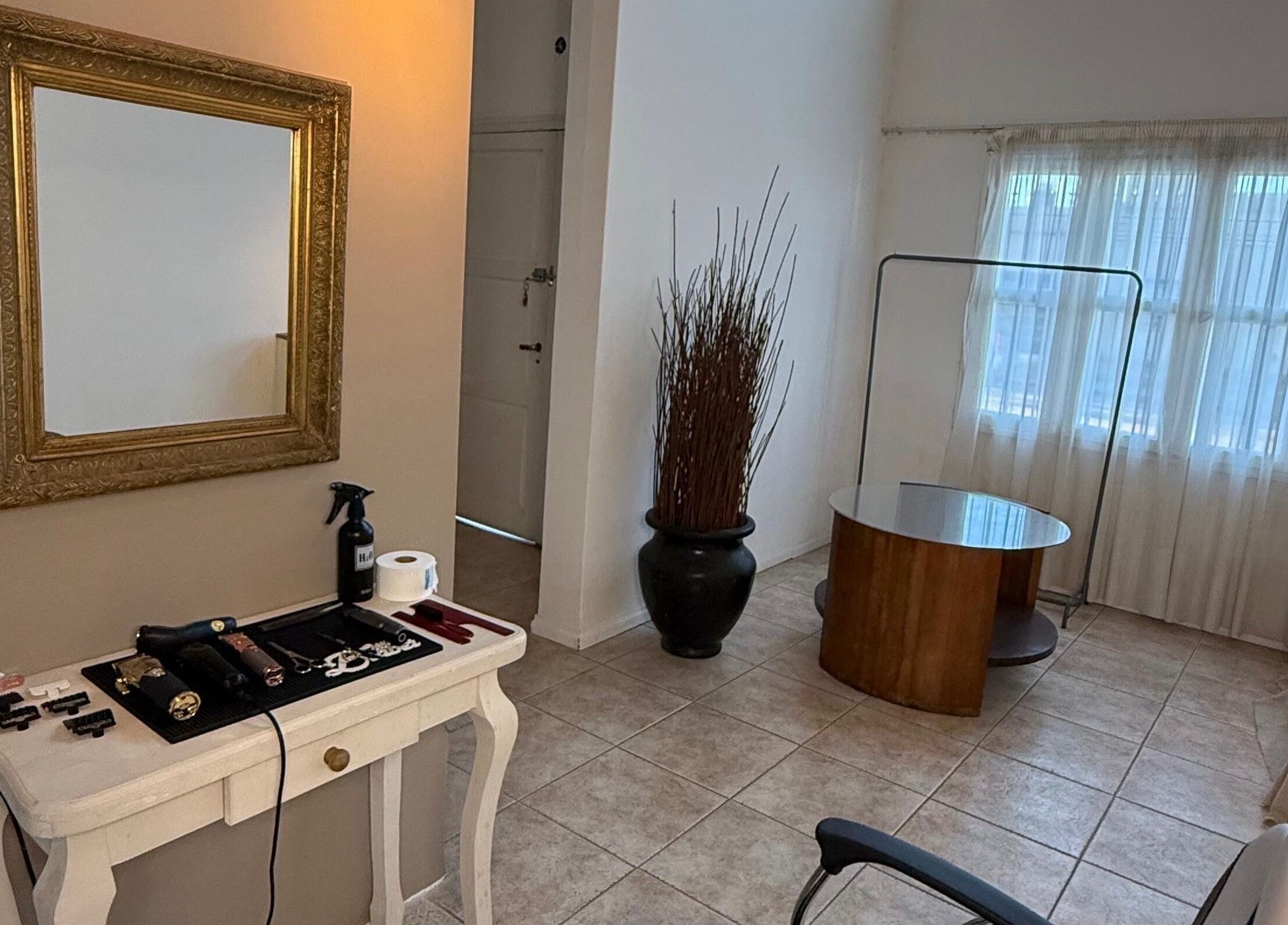 Interior acogedor de Agus barbería en Campana, Provincia De Buenos Aires, AR con espejo dorado y mesa de trabajo.