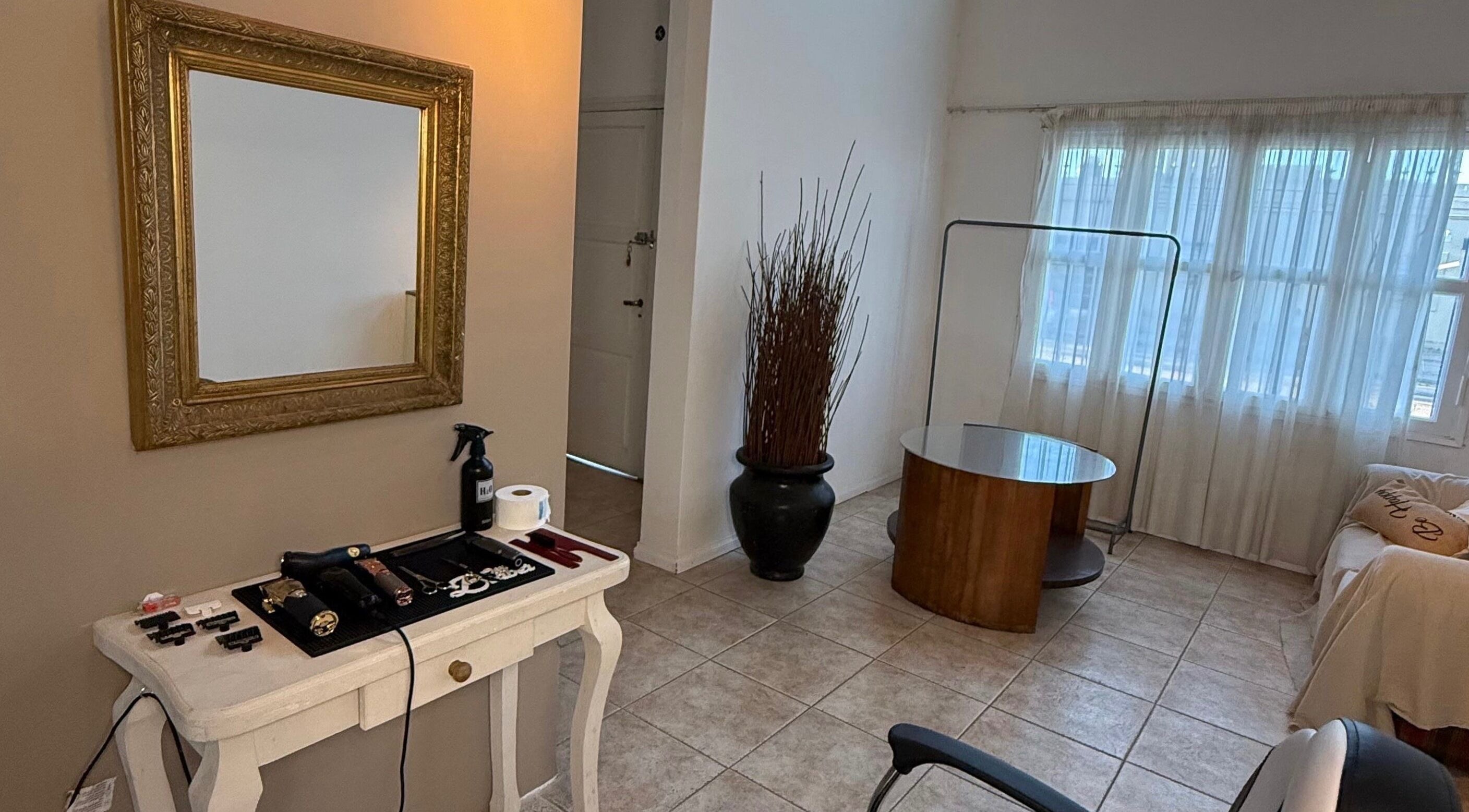 Interior acogedor de Agus barbería en Campana, Provincia De Buenos Aires, AR con espejo dorado y mesa de trabajo.