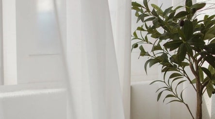 Peaceful corner at Skin Haus Aesthetics LLC, Miramar, Florida, with a lush plant by white curtains.