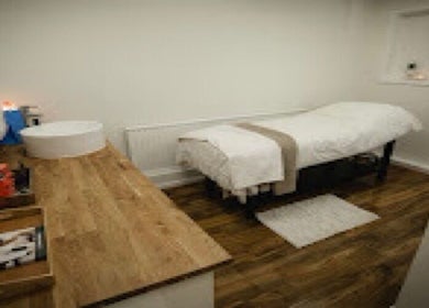Tranquil treatment room at Charliewbeauty, Aberfan, Wales, GB with a massage bed and wooden countertop.