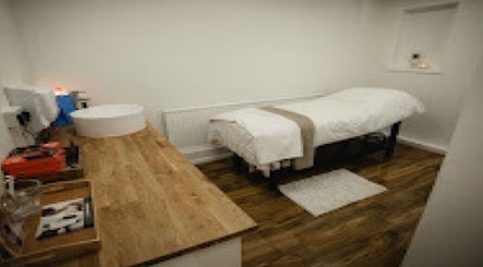 Tranquil treatment room at Charliewbeauty, Aberfan, Wales, GB with a massage bed and wooden countertop.
