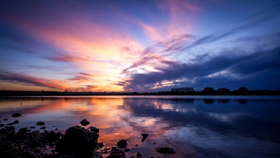 Wunderschöner Sonnenuntergang bei Wax Affairs Wiesbaden, Hessen, DE mit reflektierendem Himmel über Wasser.