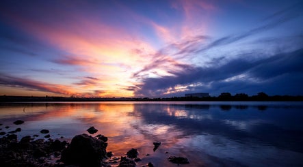 Wunderschöner Sonnenuntergang bei Wax Affairs Wiesbaden, Hessen, DE mit reflektierendem Himmel über Wasser.