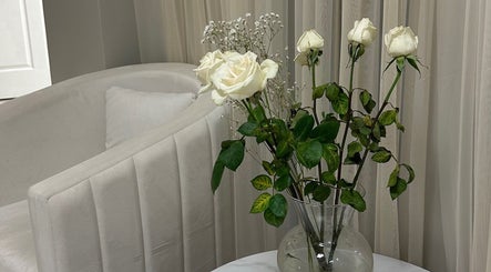 White roses in a vase beside a plush chair, enhancing 92 Lakeshore Road East in Mississauga, Ontario, CA.