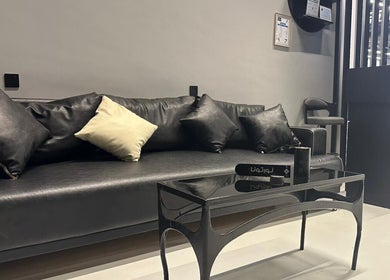 Sophisticated waiting area at Hair Zone - An Narjis, Riyadh, featuring a sleek black sofa and modern decor.