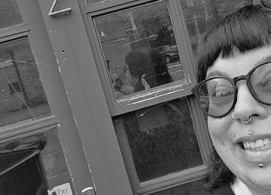 A smiling person with piercings stands outside Pearl Collective, Newbury, England, GB.