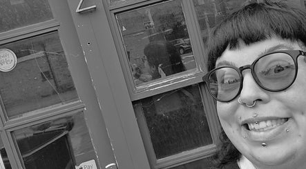 A smiling person with piercings stands outside Pearl Collective, Newbury, England, GB.