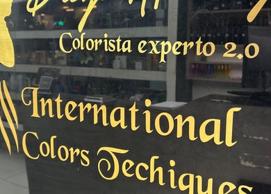 Texto dorado en ventana de AMERICAN BARBER SHOP, Marinilla, Antioquia, CO, destacando colorista experto.