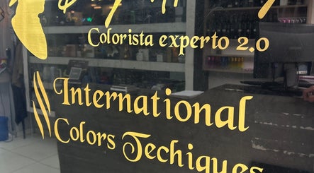 Texto dorado en ventana de AMERICAN BARBER SHOP, Marinilla, Antioquia, CO, destacando colorista experto.