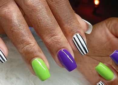 Close-up of colorful nail art at Cialeyah Beauty Bar, Philipsburg, SX showcasing vibrant stripes and polish.