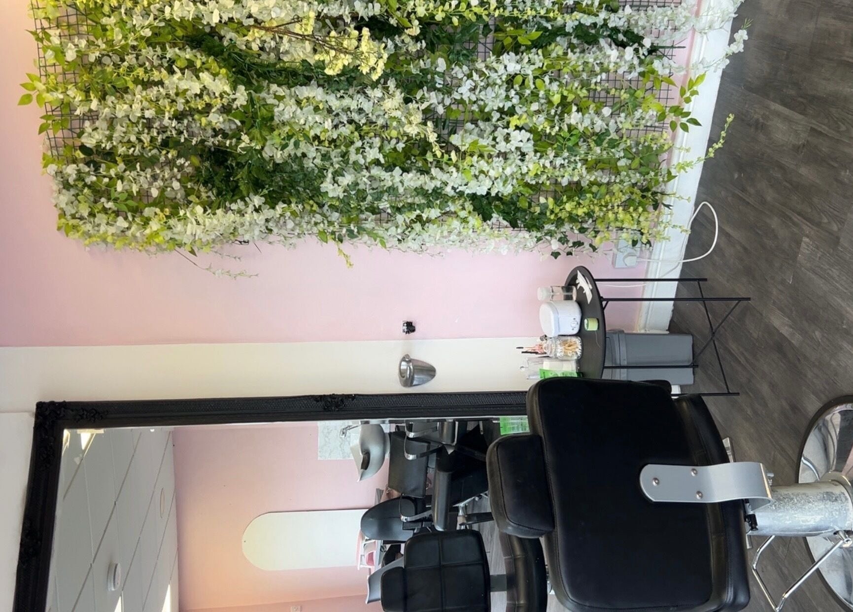 Elegant styling chair by floral wall at Beautiful You, Birmingham, England, GB inviting relaxation and beauty care.