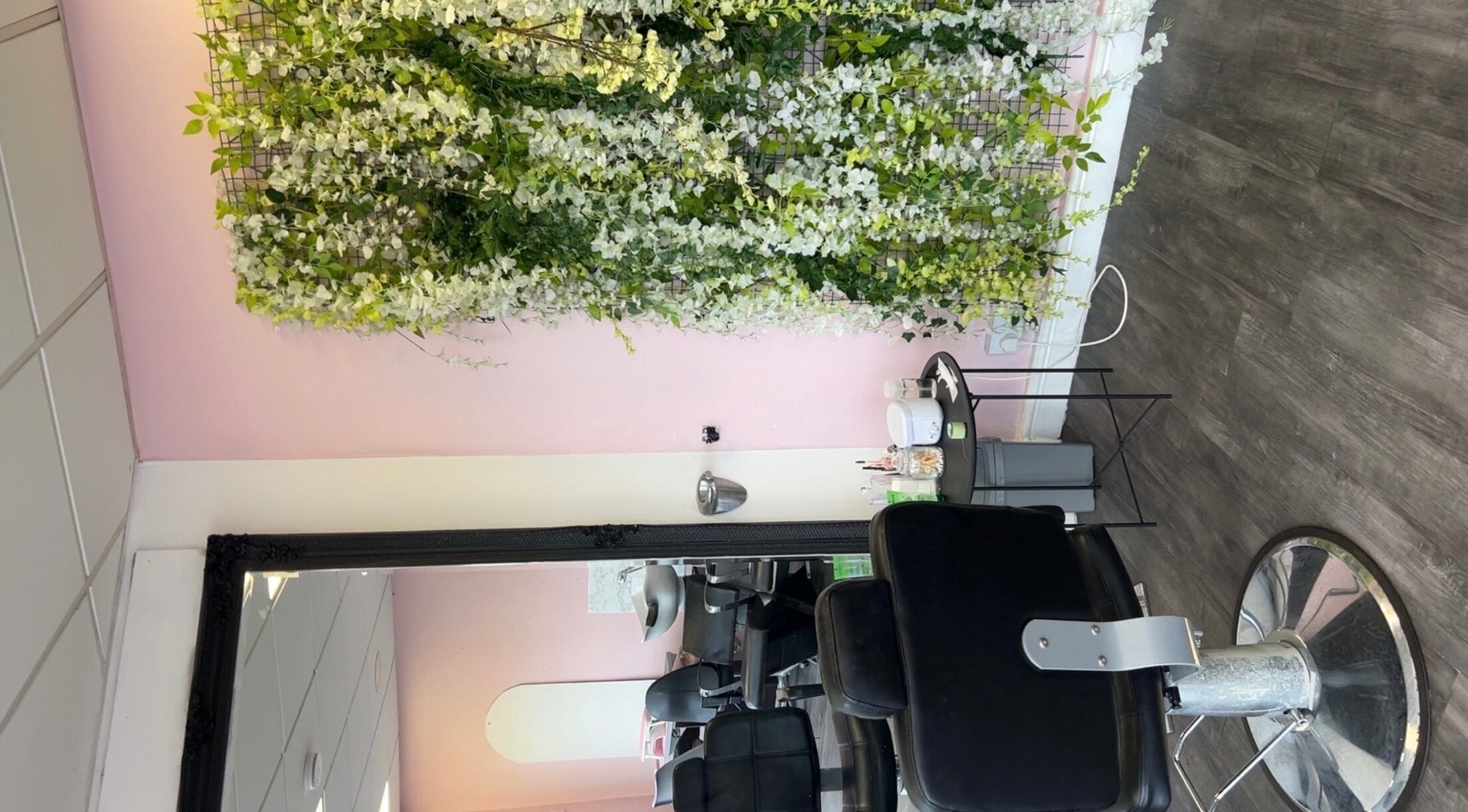 Elegant styling chair by floral wall at Beautiful You, Birmingham, England, GB inviting relaxation and beauty care.