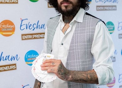 Tattooed magician holding cards at Slick Magic, Stratford Upon Avon, GB, showcasing unique flair and style.