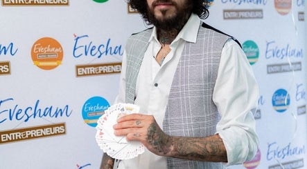 Tattooed magician holding cards at Slick Magic, Stratford Upon Avon, GB, showcasing unique flair and style.