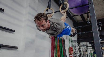 Man performing gymnastic rings exercise at Resalve LTD, Coventry, England, GB gym facility.