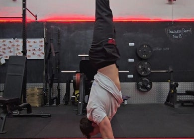 Person performing a handstand in a gym at Resalve LTD, Coventry, England, GB with red neon lights.