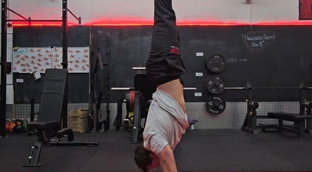 Person performing a handstand in a gym at Resalve LTD, Coventry, England, GB with red neon lights.