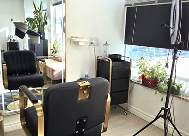 Stylish interior of Y's Hair Lab in Toronto, Ontario, CA featuring a chic black and gold salon chair by a large mirror.