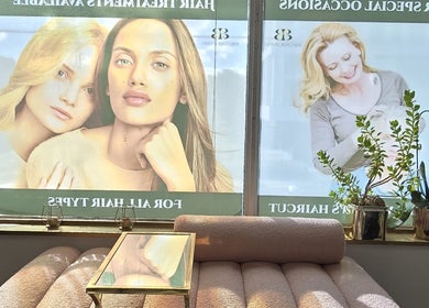 Cozy seating area with plants at Y's Hair Lab in Toronto, Ontario, CA, featuring large model posters.