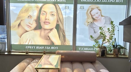 Cozy seating area with plants at Y's Hair Lab in Toronto, Ontario, CA, featuring large model posters.
