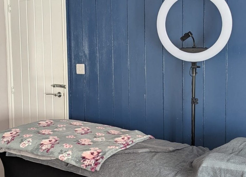 Cozy treatment room at Glam Glow Grace, Mapplewell, England, with a massage table and ring light.