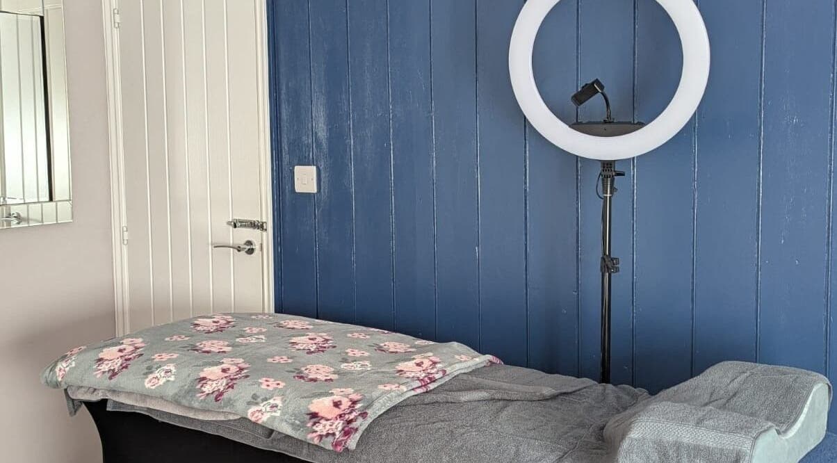 Cozy treatment room at Glam Glow Grace, Mapplewell, England, with a massage table and ring light.