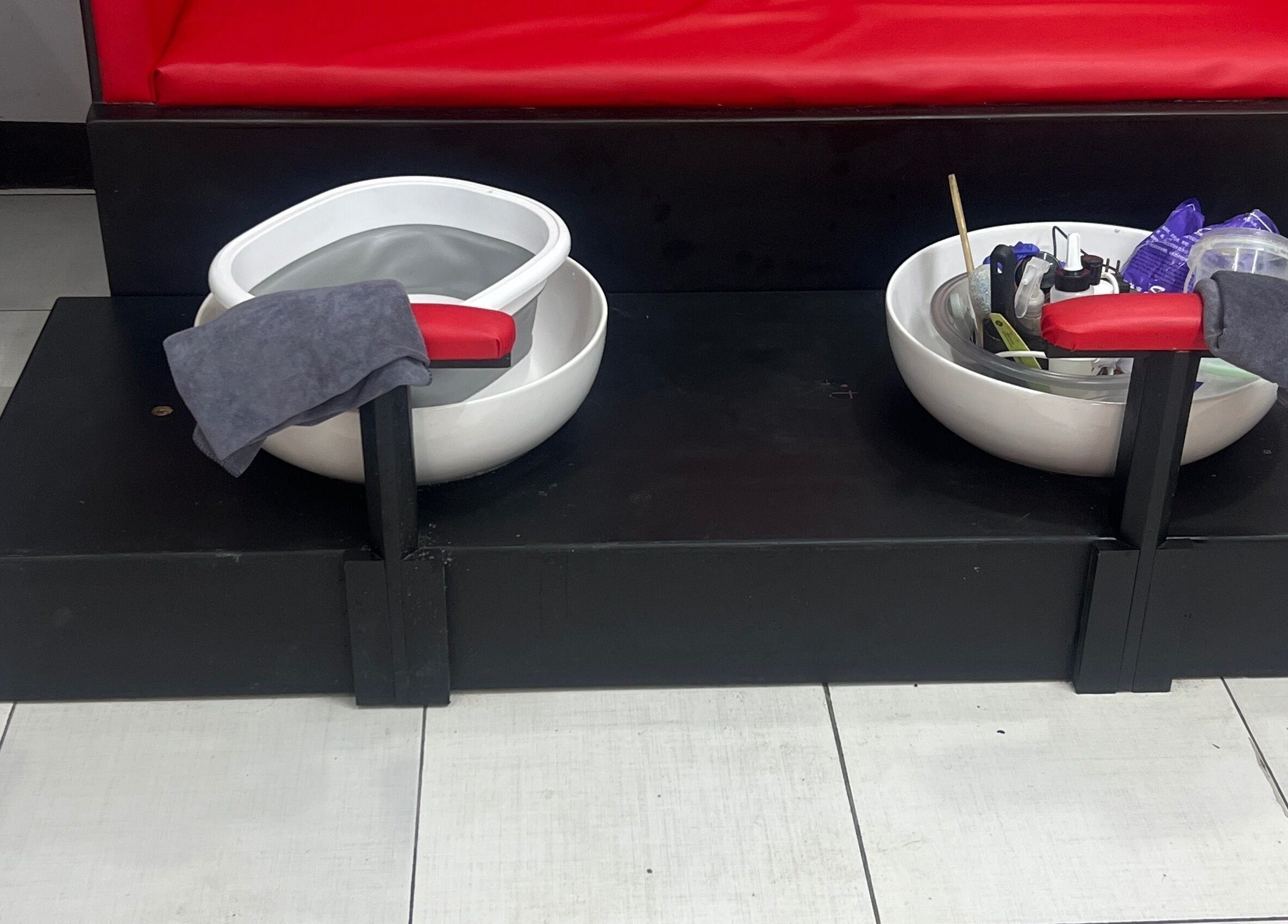 Pedicure spa bowls at Stargirl Chel Beauty Salon in Paramaribo, SR, featuring red seats and essential tools.