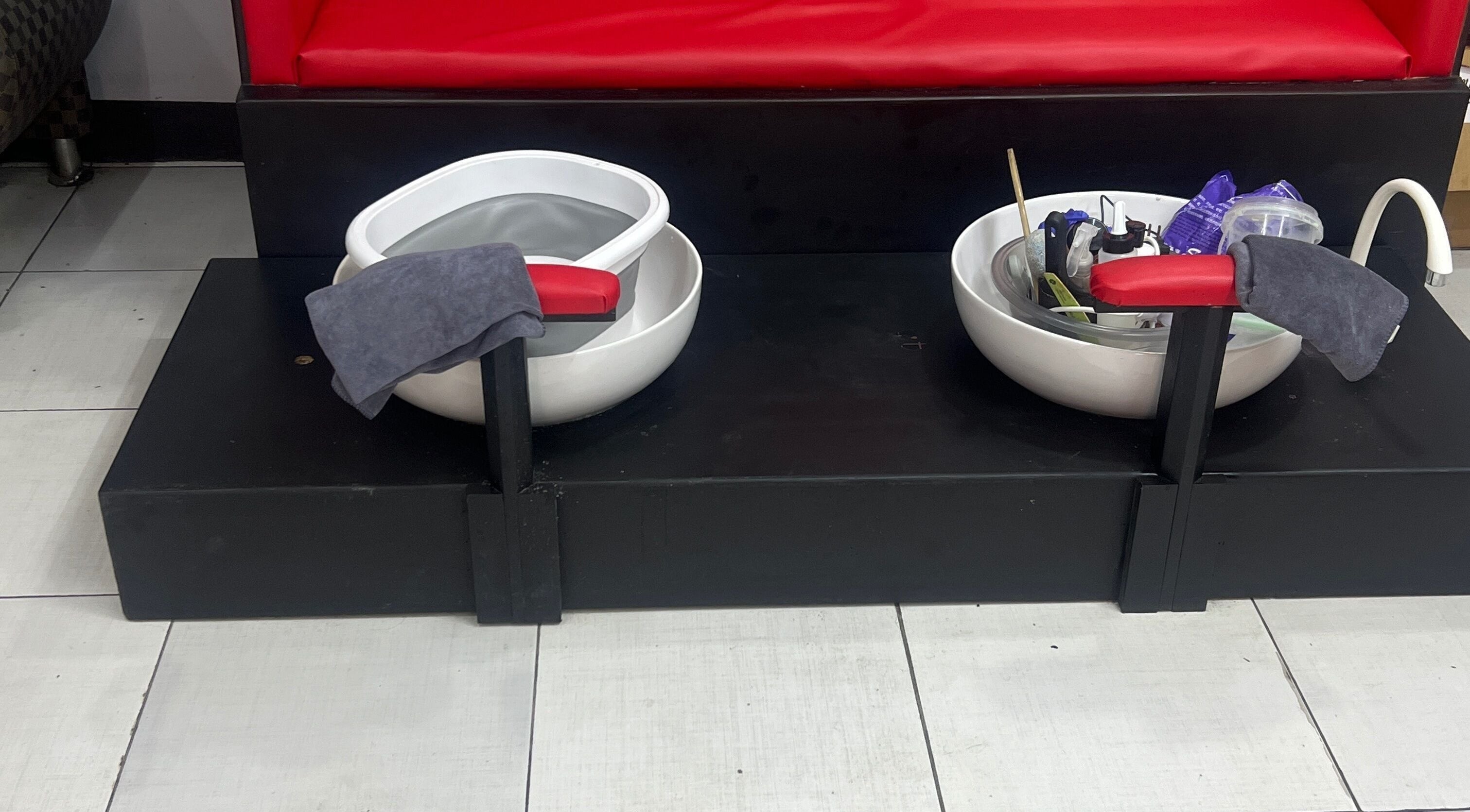 Pedicure spa bowls at Stargirl Chel Beauty Salon in Paramaribo, SR, featuring red seats and essential tools.