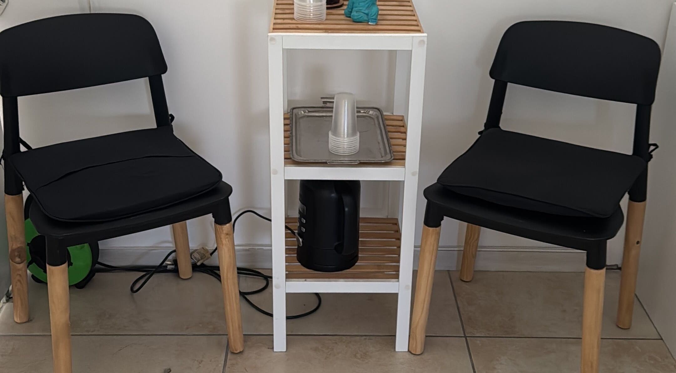 Zona de espera en Ser Piel Real, S2000ein, Santa Fe, AR, con sillas negras y mesa auxiliar.