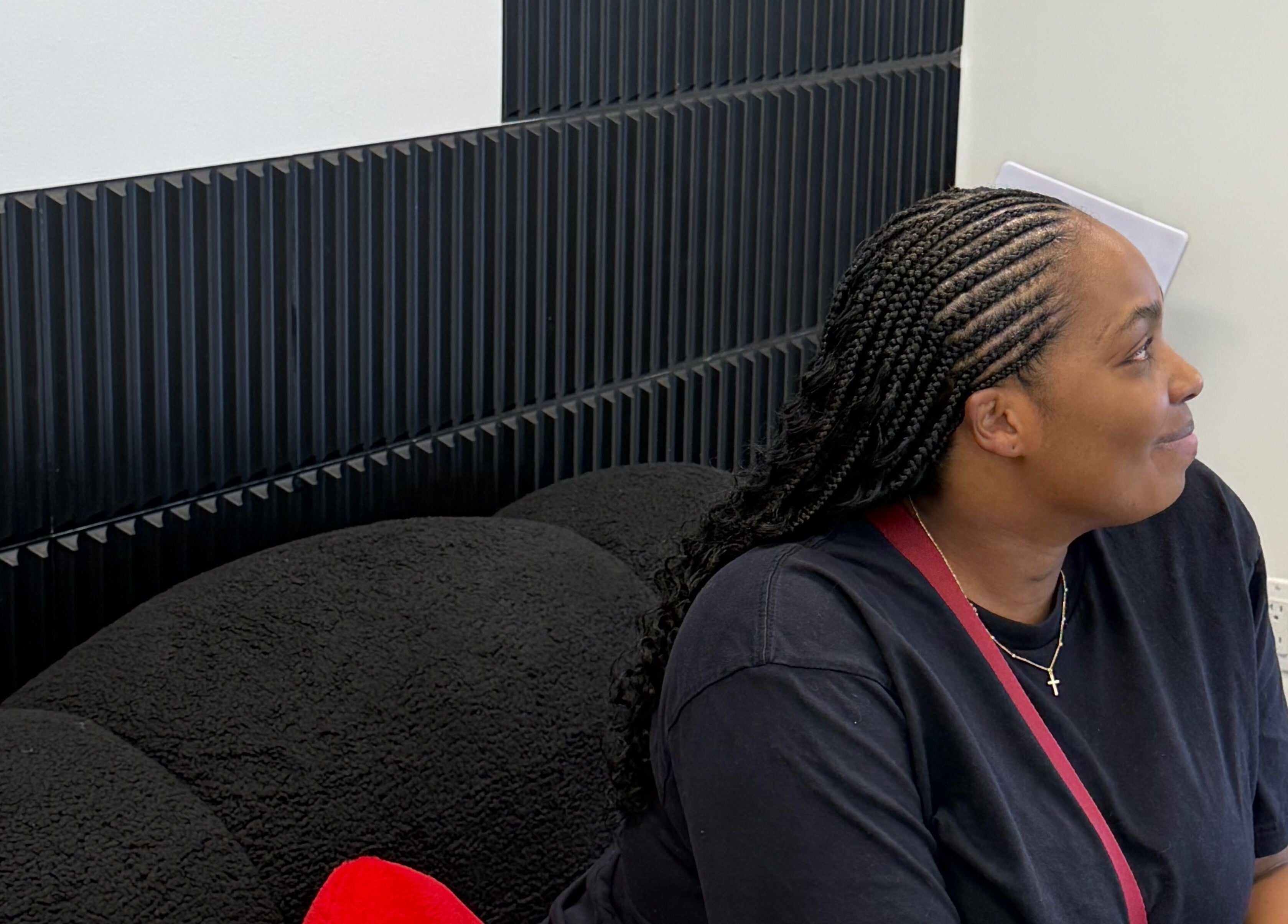 Woman relaxing on a black couch in Funmi’s salon, New York, New York, US, showcasing a stylish braid.