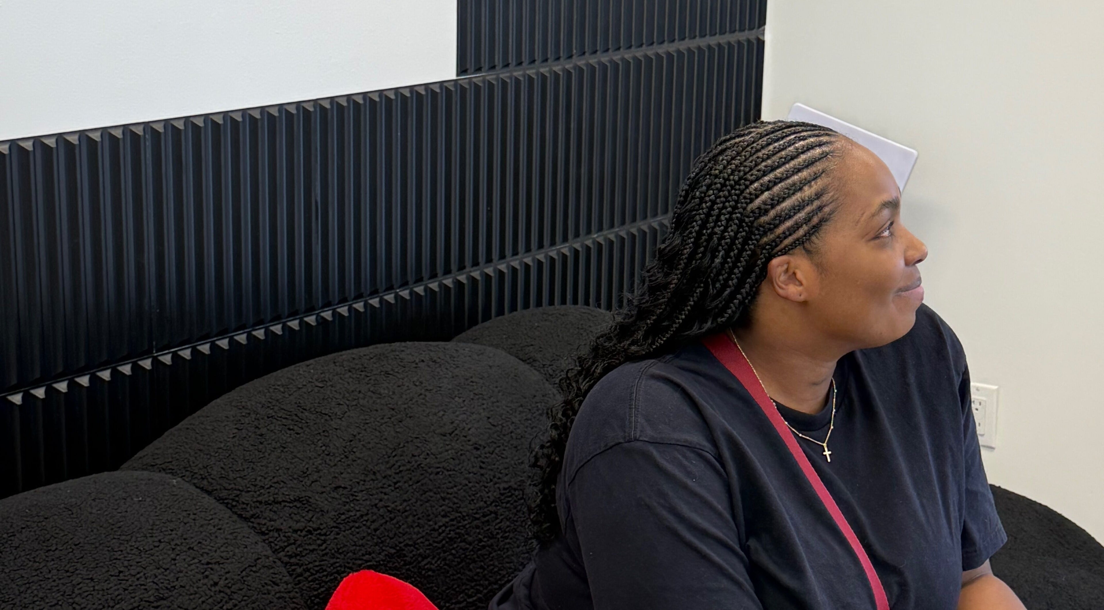 Woman relaxing on a black couch in Funmi’s salon, New York, New York, US, showcasing a stylish braid.