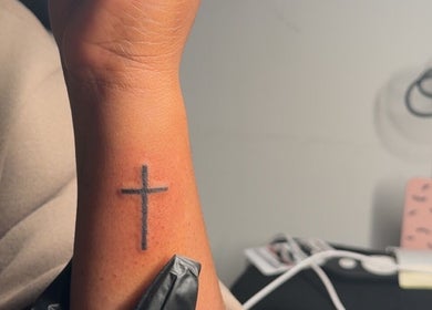 Simple cross tattoo on wrist at De Effys Effectttt, Ilford, England, GB.