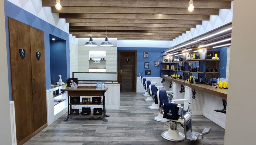 Interni eleganti di Il Barbiere Giussano a Giussano, Lombardia, IT con sedie blu e scaffali raffinati.