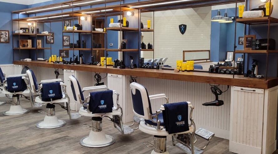 Interno di Il Barbiere Curno, Curno, Lombardia, IT: poltrone vintage e prodotti di bellezza in esposizione.