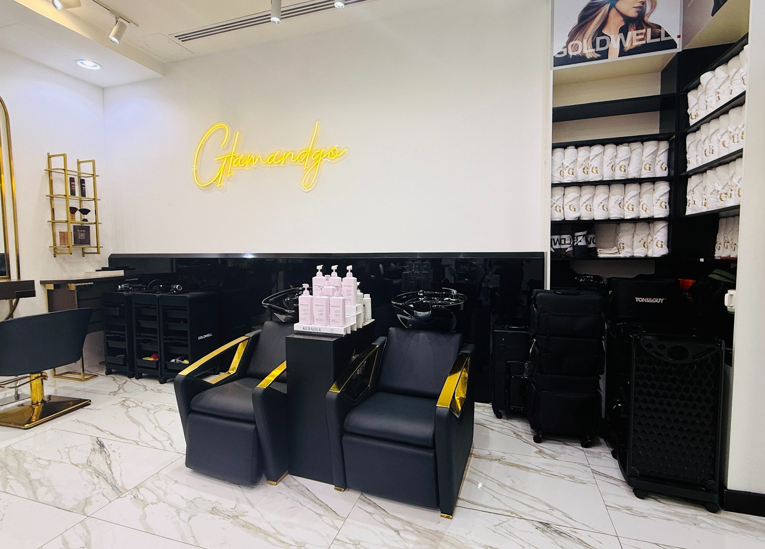 Interior of Glam & Go Salon JVC, Dubai featuring stylish chairs and products on marble flooring.