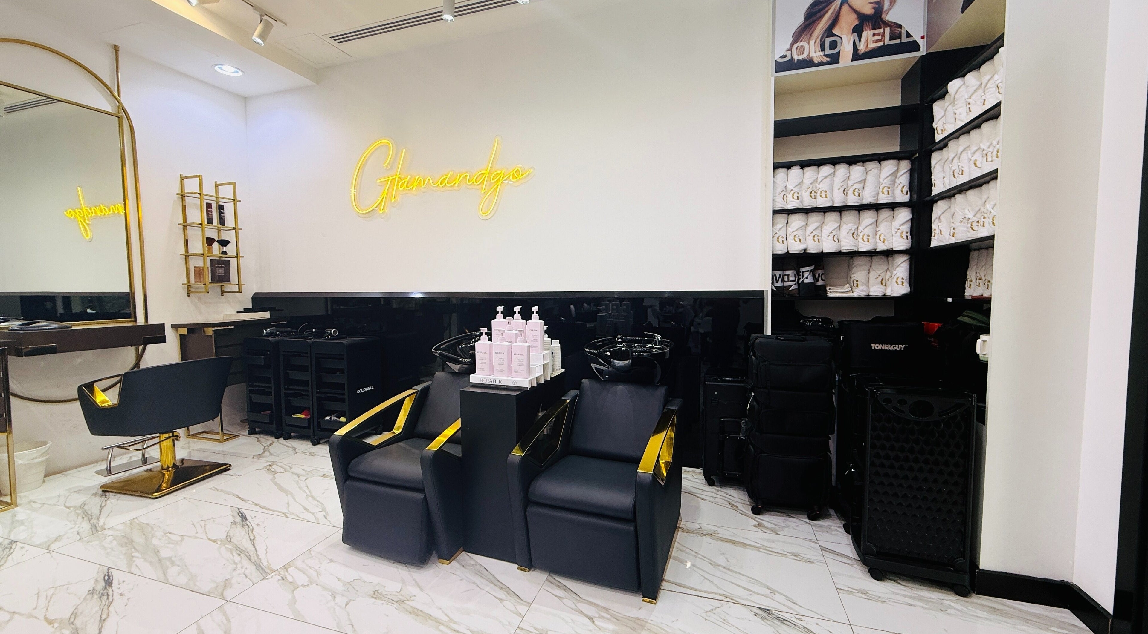Interior of Glam & Go Salon JVC, Dubai featuring stylish chairs and products on marble flooring.