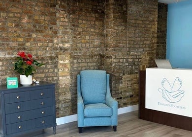 Inviting reception area at Alina N. Sports Massage, London, England, GB, featuring a chic chair and wooden decor.