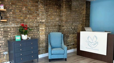 Inviting reception area at Alina N. Sports Massage, London, England, GB, featuring a chic chair and wooden decor.