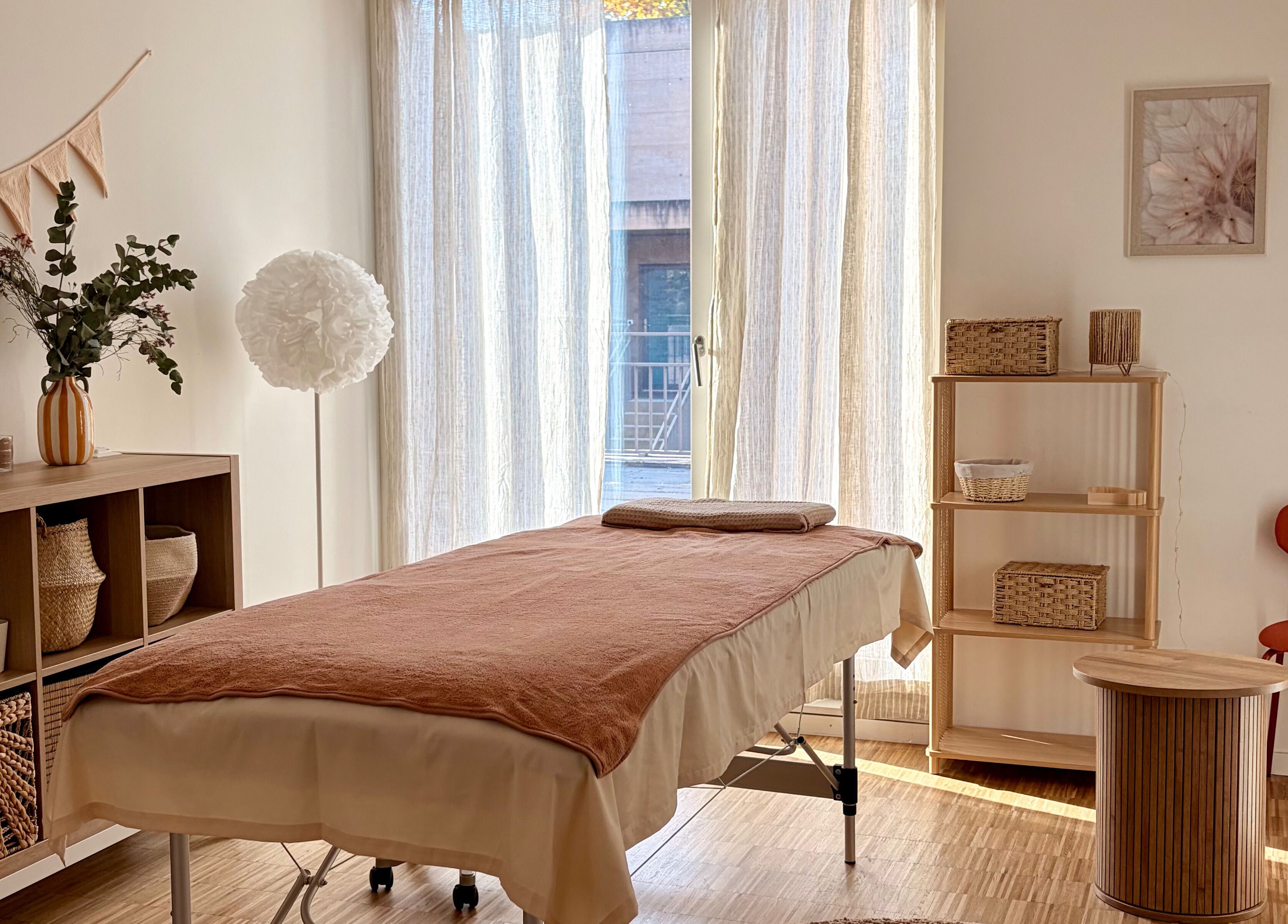 Salle de traitement paisible à Flower Studio, Corsier, Genève, CH, avec lit de massage et décoration chaleureuse.