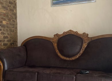 Vintage sofa in El Roi Nails, Vereeniging, Gauteng, ZA, with ornate woodwork against a brick wall.
