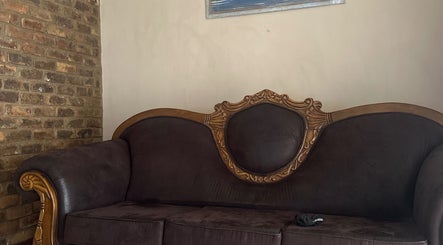 Vintage sofa in El Roi Nails, Vereeniging, Gauteng, ZA, with ornate woodwork against a brick wall.